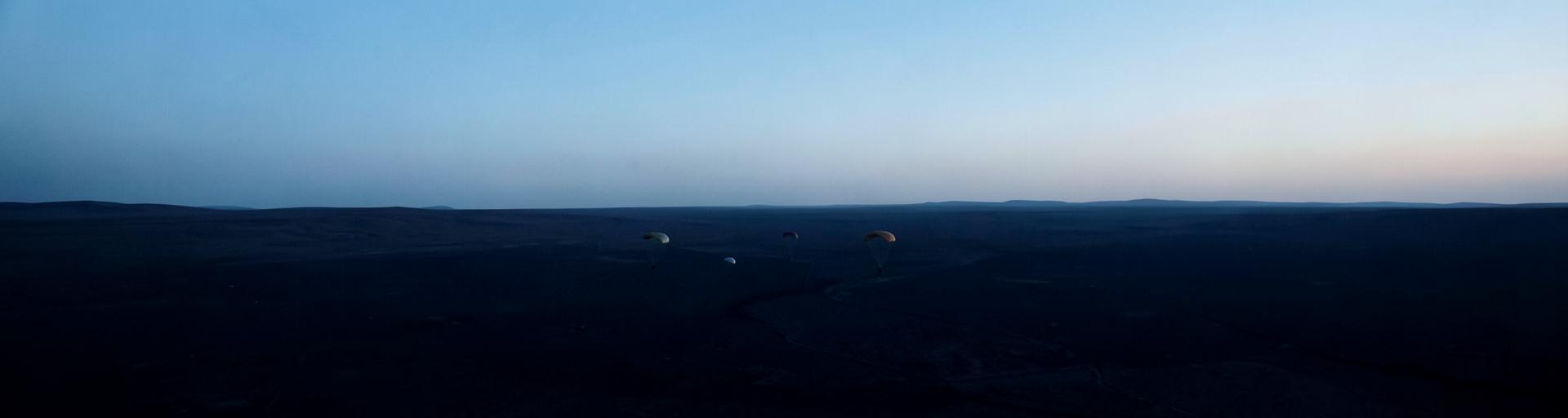 Canopies descending over dark terrain